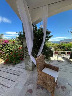 a wicker chair sitting on a patio with a canopy at Rosa's House in Santa Flavia