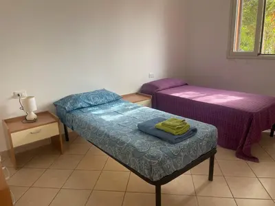 a room with two beds and a table with a bedskirts at Villetta 200mt mare e piscina in Campofelice di Roccella