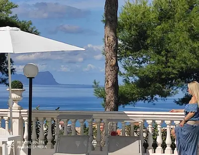 a woman sitting on a fence looking at the ocean at Villa Nunziatella Badia in Trappeto