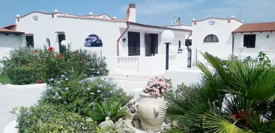 a white house with flowers in a yard at Villa Nunziatella Badia in Trappeto