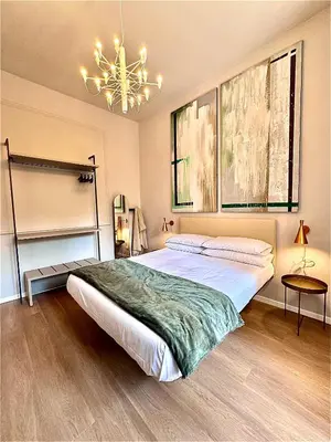 a bedroom with a large bed and a chandelier at YourLife Suite1 - Deliziosa casa con terrazzino in Palermo