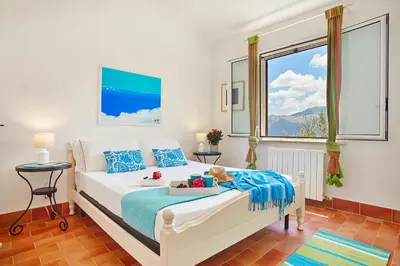 a bedroom with a white bed with blue pillows at Villa Conchiglia - Scopello-Villas in Scopello