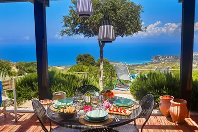 a table on a patio with a view of the ocean at Villa Conchiglia - Scopello-Villas in Scopello