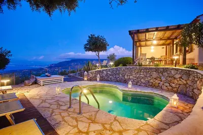 a swimming pool with a stone wall next to a house at Villa Conchiglia - Scopello-Villas in Scopello