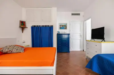 a bedroom with an orange bed and a blue curtain at Terrazza sul mare in Santa Flavia