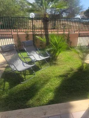 two chairs sitting in a yard next to a fence at Villetta Viola in San Vito lo Capo