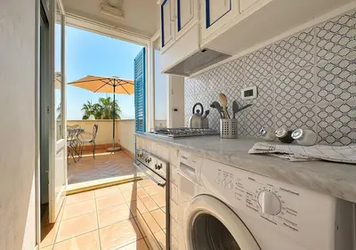 a kitchen with a washing machine and a patio at Solemar Sicilia - Palazzo Eos e Aura in Porticello