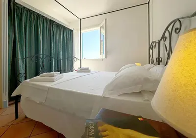 a bedroom with a large white bed with a window at Solemar Sicilia - Palazzo Eos e Aura in Porticello