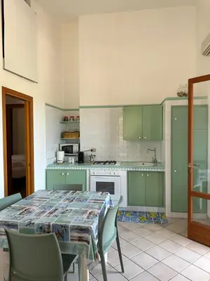 a kitchen with green cabinets and a table with chairs at Cocciu D'amuri Home - Scopello in Scopello
