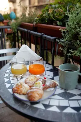 a table with a plate of food and two glasses of orange juice at Porto Felice Home Palermo in Palermo