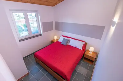 a small bedroom with a red bed and a window at Villa Cicas sul mare in Campofelice di Roccella