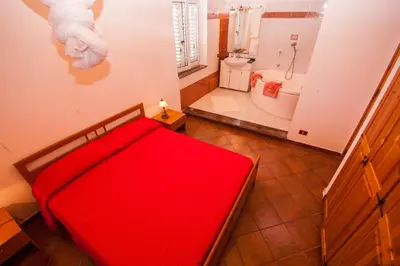 a bedroom with a red bed and a bath tub at Villa Cicas sul mare in Campofelice di Roccella