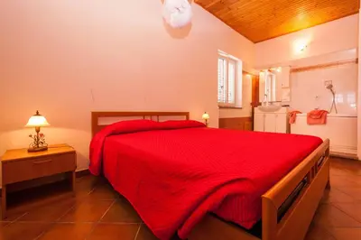 a bedroom with a red bed and a bathroom at Villa Cicas sul mare in Campofelice di Roccella
