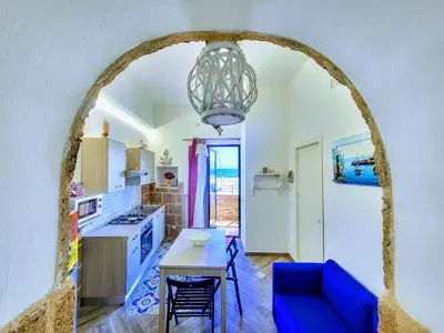 a kitchen with a table and a blue couch at Seafront House Gabbiano Blu in Santa Flavia
