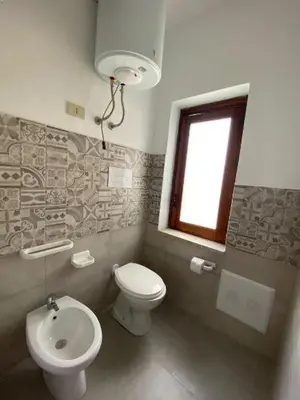 a bathroom with a toilet and a sink and a window at Blunda Holiday Home in Castellammare del Golfo