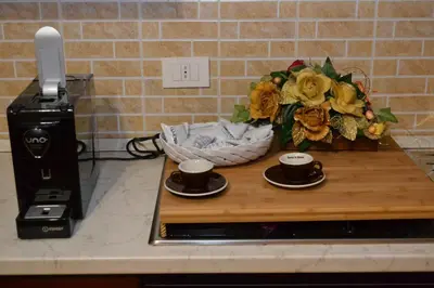 two cups of coffee on a counter with a vase of flowers at B&B Jolly house Bolognetta in Bolognetta