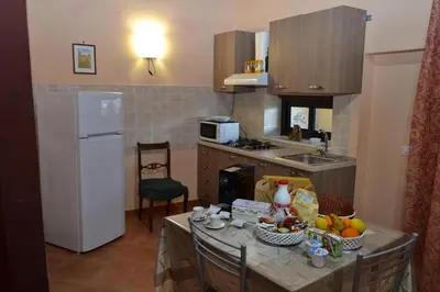 a kitchen with a table and a white refrigerator at B&B Jolly house Bolognetta in Bolognetta