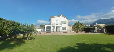 a white house with a lawn in front of it at Casa di Lele in Carini