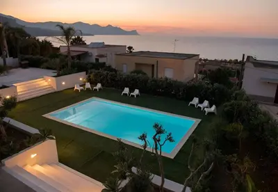 a backyard with a swimming pool and chairs and the ocean at Villa Dwellings With Pool For Exclusive Use in Alcamo