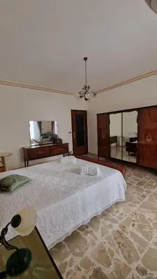 a bedroom with a large white bed and a mirror at Casa vacanza-Il Sole di Sicilia in Vita