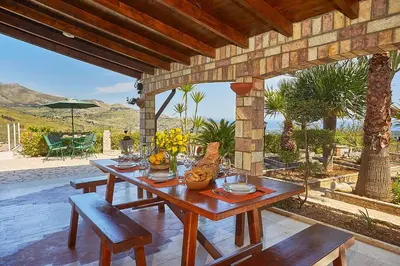 a wooden table and benches on a patio at Villa del Poggio in Scopello
