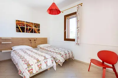 a bedroom with two beds and a red chair at Villa delle Stelle in Scopello