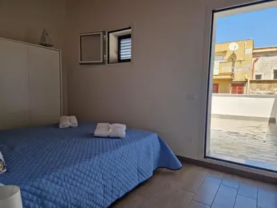 a bedroom with a blue bed and a large window at Il Cavaliere Apartment in Capaci