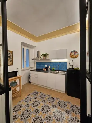 a kitchen with white cabinets and blue tiles at Casa Novelli 22 - Vista sulla Cattedrale in Palermo