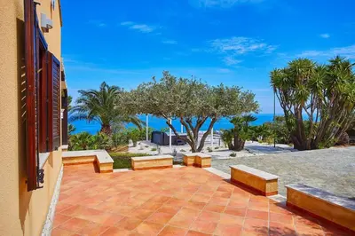 a patio with benches and a view of the ocean at Villa del Drago in Scopello