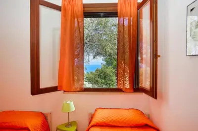 a bedroom with a window with an orange curtain at Villa del Drago in Scopello