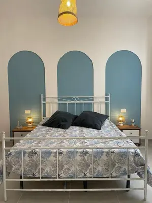 a bed in a bedroom with two tables and a lamp at Coralìa in San Vito lo Capo
