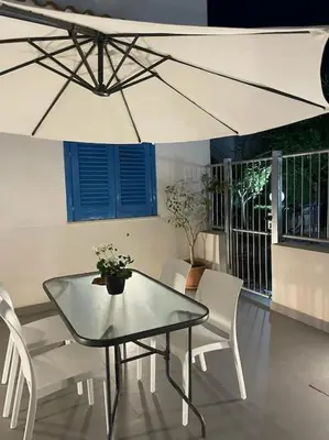 a table and chairs with a white umbrella at Coralìa in San Vito lo Capo