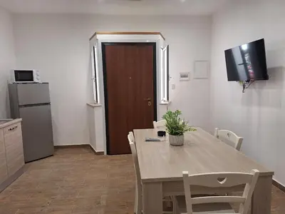 a room with a table and a kitchen with a door at Casa Sabo Apartment in Palermo