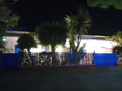 a blue fence in front of a building with palm trees at ai colori di Giggia in Isola delle Femmine