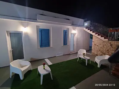 a living room with white chairs and a staircase at Tramonti d'Alba in Terrasini