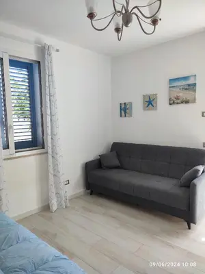 a living room with a couch and a window at Tramonti d'Alba in Terrasini