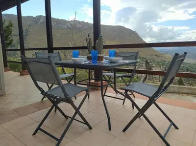 a table and chairs on a balcony with a view at Rifugio Riserva Grotta Mazzamuto in Altavilla Milicia