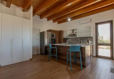 a kitchen with a counter and two blue stools at Villa Ginevra in Santa Ninfa