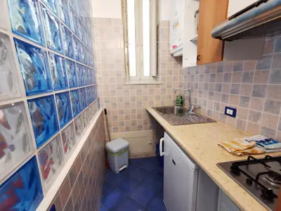 a small kitchen with blue tiles on the wall at Appartamento Tirreno Mondello in Palermo