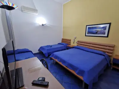 a room with two beds and a desk with a television at Appartamento Tirreno Mondello in Palermo