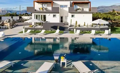 a person sitting in a chair next to a swimming pool at Villa Luxury Eden di Sofia in Partinico