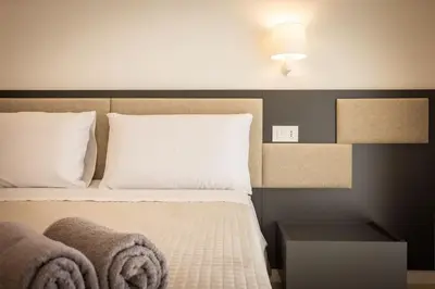 a bedroom with a bed with white sheets and pillows at Luxury Jacuzzi Villa Nettuno in Palermo