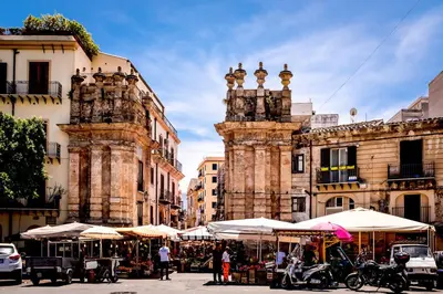 a street with tables and umbrellas in front of buildings at mastro casa vacanza in Palermo