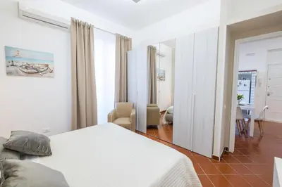 a bedroom with a white bed and a dining room at MEC apartment in Palermo