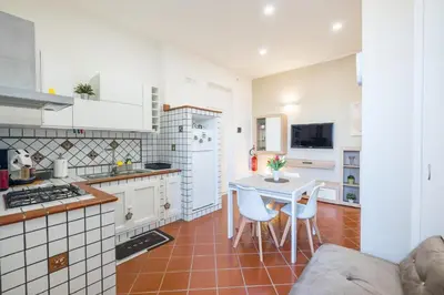 a kitchen with white cabinets and a table and chairs at MEC apartment in Palermo
