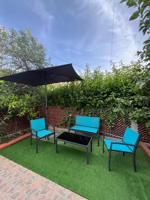 three chairs and a table with an umbrella on the grass at Vito's holiday house in Palermo