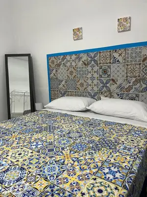 a bedroom with a bed with a patterned headboard and a mirror at Vito's holiday house in Palermo