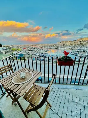 a table and chairs on a balcony with a harbor at CalaMia in Palermo