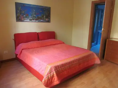 a red bed in a bedroom with a painting on the wall at Panormus Home&Apartaments in Palermo