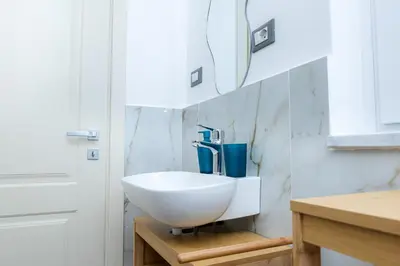 a bathroom with a white sink on a wall at Vanda's Terrace in Palermo